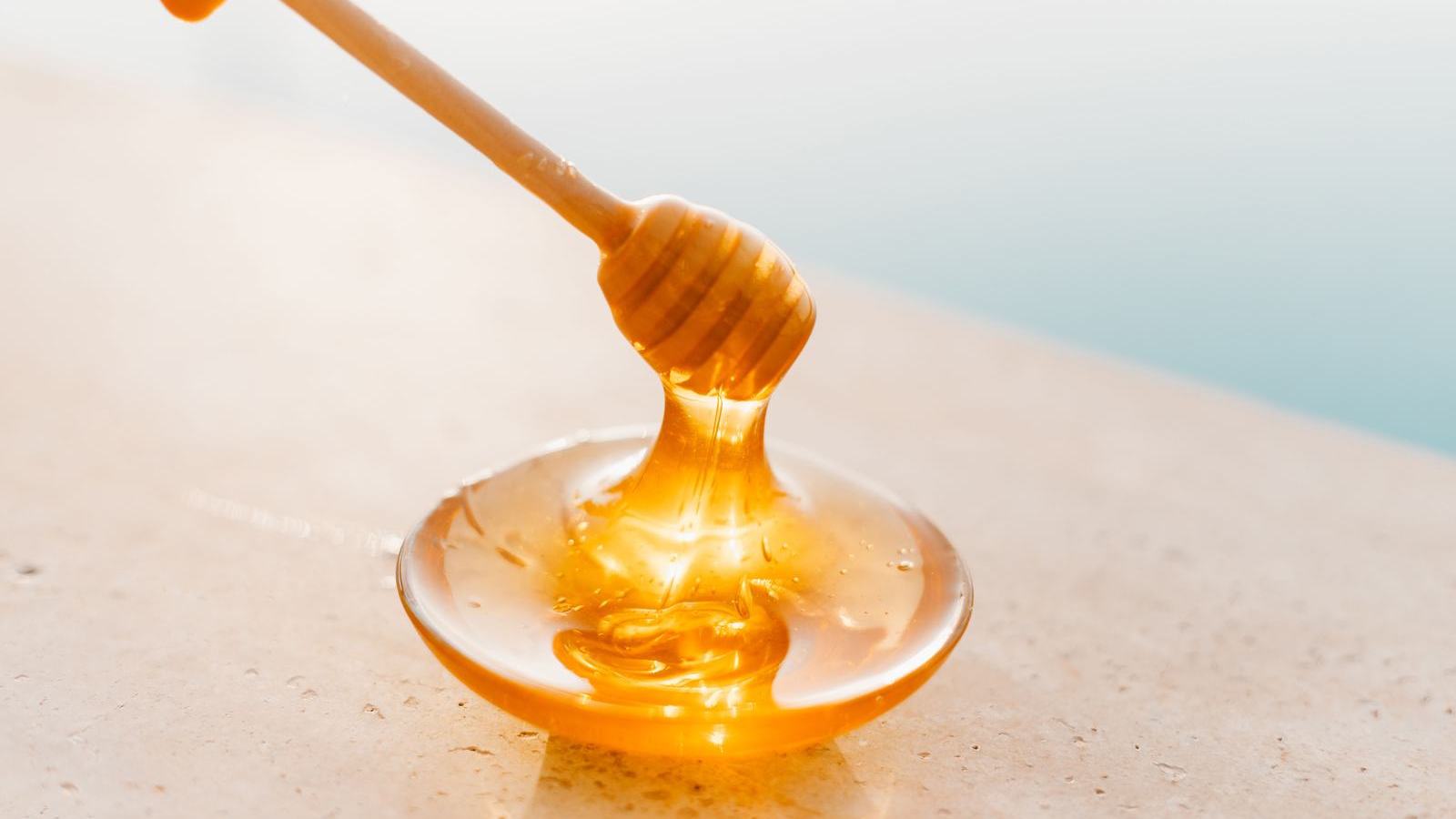 Natural Pakistani honey drizzling from a wooden spoon